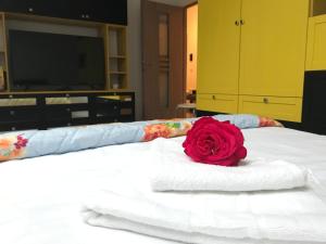 a red rose sitting on top of a white bed at Eli’s Apartament in Piatra Neamţ