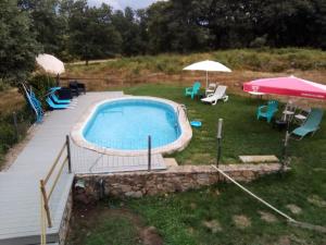 a backyard with a swimming pool and an umbrella and chairs at Eira Velha in Portalegre
