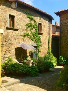 a stone building with a table and an umbrella at Il Priorato in Pescia