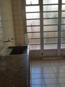 une cuisine avec un évier dans une pièce avec des fenêtres dans l'établissement Casa de praia Boracéia, à Bertioga