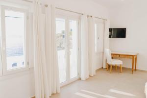 a white room with a desk and windows at BAY VIEW RESIDENCE in Mikonos