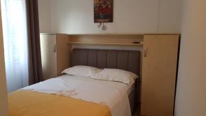 a bedroom with a bed with a wooden headboard at Apartmani Ljerka Malinska in Malinska