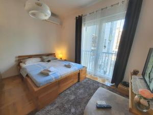 a bedroom with a bed and a large window at Apartman Borislava in Trebinje
