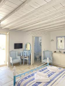 um quarto com uma cama e cadeiras e uma televisão em Blue Harmony Suites of Mykonos em Míconos