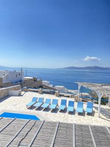 um grupo de espreguiçadeiras azuis e o oceano em Blue Harmony Suites of Mykonos em Míconos