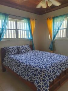 a bedroom with a bed with a blue comforter and two windows at Fishtails Palms - Tamarind in Stuart Manor