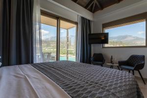 a bedroom with a bed and two chairs and windows at Lighthouse Apartments in Stoupa