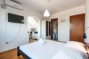 a bedroom with a white bed and a tv on the wall at Apartments & Rooms Strčić Krk in Krk