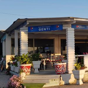 a restaurant with pots of plants in front of it at Hotel Restorant Genti Peshkatari in Orikum