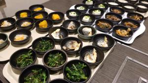 um tabuleiro cheio de tigelas pretas de comida numa mesa em MyHotel Okazaki em Okazaki
