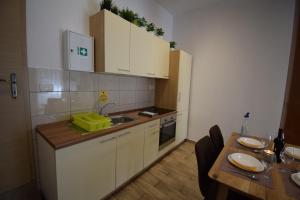 a kitchen with white cabinets and a wooden table at City Core Apartment in Koper