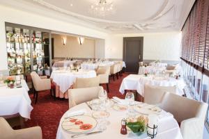 a restaurant with white tables and chairs and a chandelier at Logis Hôtel restaurant LE MEDICIS in Blois