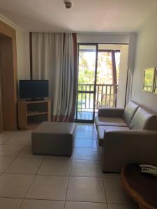 a living room with a couch and a television at Flat no Beach Class Muro Alto in Porto De Galinhas