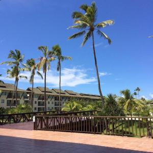 a balcony with palm trees and a building at Flat no Beach Class Muro Alto in Porto De Galinhas