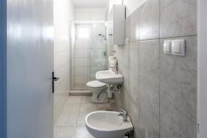 a white bathroom with a toilet and a sink at Apartments & Rooms Strčić Krk in Krk