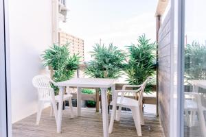 a white table and chairs on a balcony with plants at Hotel Atlantique in Mimizan-Plage