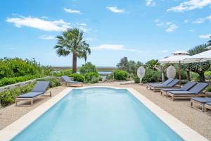 a swimming pool with chairs and umbrellas next to the ocean at Casa da Ria in Tavira