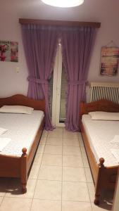 two beds in a room with purple curtains at Antonioy Apartment Metewra in Kalabaka