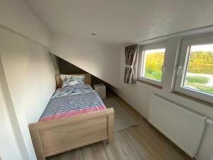 uma pequena cama num pequeno quarto com duas janelas em Ferienwohnung am Teufelsmoor -KEINE MONTEURE- em Klein Wehnendorf
