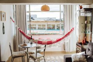 a hammock in a room with a large window at Apto a beira mar no Centro - WIFI 200MB - TV Smart - Cozinha equipada - Portaria 24h - Ar condicionado in Rio das Ostras