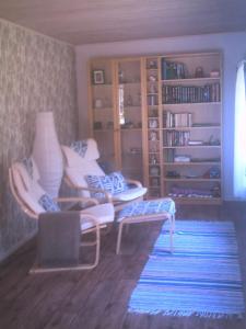- un salon avec des chaises blanches et une étagère à livres dans l'établissement Holiday House in Oknö, Mönsterås, à Mönsterås