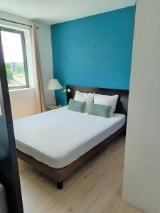 een slaapkamer met een groot bed met een blauwe muur bij Appartement ensoleillé au pied du Futuroscope in Chasseneuil-du-Poitou