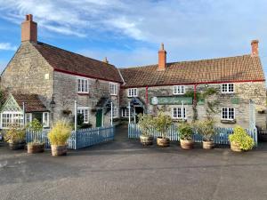 an old brick building with potted plants in front of it at The Lion at West Pennard in West Pennard