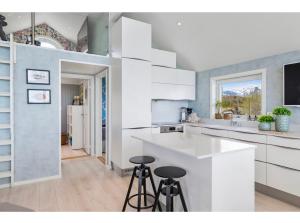 a kitchen with white cabinets and bar stools at Atlantic Panorama in Vevang