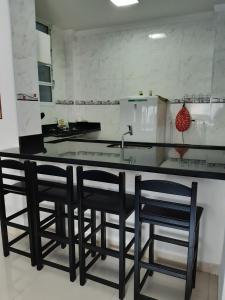 a kitchen with black chairs and a kitchen counter at Kitnet Guarujá Pitangueiras (sem garagem) in Guarujá