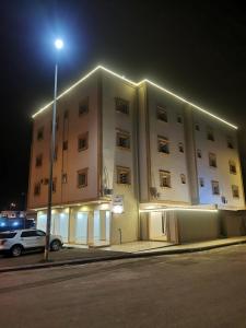 un grande edificio con un lampione davanti di المبيت للشقق الفندقية a Sirr Āl Ghalīz̧