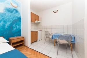 una pequeña cocina con mesa y sillas en una habitación en Apartmani Petracie, en Drvenik