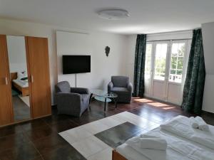 a living room with a bed and chairs and a television at Villa Pelso in Balatongyörök