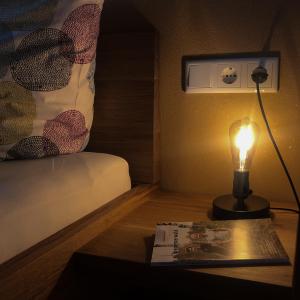 uma lâmpada sobre uma mesa ao lado de uma cama com um livro em Ferienwohnung Schnepfau 24 em Schnepfau