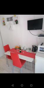a kitchen with a table with red chairs and a tv at Room Dragica in Dubrovnik