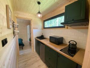 a kitchen in a tiny house with a stove at Ostoja Orżyny, Dom nr 2 - Zielono mi in Dźwierzuty +13 photos