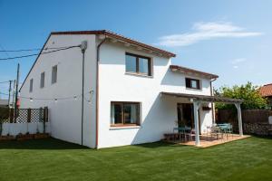 una casa blanca con un patio verde en La Casita de Melón, en Suances