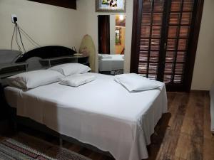 1 dormitorio con 1 cama blanca grande y 2 almohadas en Chácara Águas Claras en Monte Sião