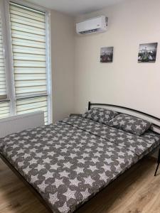 a bed with a black and white comforter in a bedroom at 0263-2 Смарт-апартаменты ЖК «Счастливый» in Kyiv