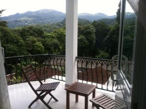 two chairs on a balcony with a view of the mountains at Peradeniya Rest House in Kandy