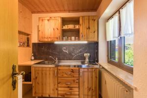 eine Küche mit Holzschränken, einem Waschbecken und einem Fenster in der Unterkunft Ferienwohnung Heinrich in Gmund am Tegernsee