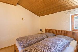 Bett in einem Zimmer mit Holzdecke in der Unterkunft Ferienwohnung Heinrich in Gmund am Tegernsee