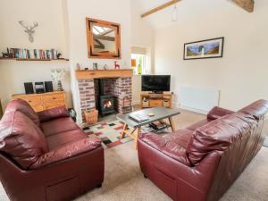 a living room with two leather couches and a fireplace at Hemmel Cottage in Alnwick