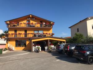 a large yellow building with cars parked in a parking lot at Sobe ROOMS TEA in Buje