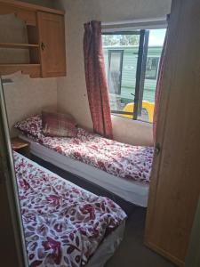 twee bedden in een kleine kamer met een raam bij Lochlands caravan park X(6) in Forfar