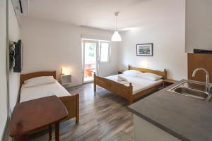 a room with two beds and a kitchen with a sink at Apartments & Rooms Strčić Krk in Krk