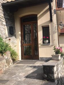 uma casa com uma porta de madeira com flores numa janela em Reginaldo's home Bed&Breakfast em Nesso