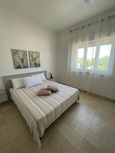 een witte slaapkamer met een groot bed met 2 kussens bij SINE TEMPORE Beach Holiday Home in Maruggio