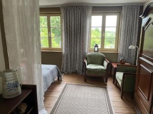 a bedroom with a bed and a chair and windows at Ferienwohnung Burgplatz 1 in Plau am See