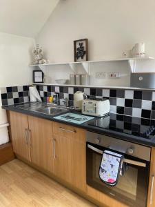 a kitchen with a sink and a stove top oven at Cwt Mochyn in Corwen