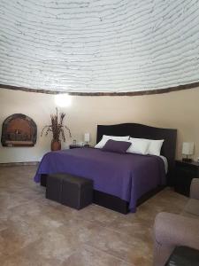 a bedroom with a bed with a purple bedspread at Hacienda Eco-Domes in Valle de Guadalupe